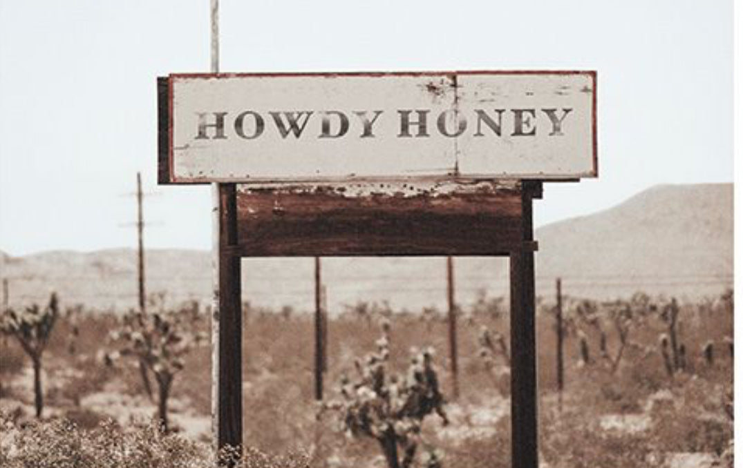 Vintage-style 'Howdy Honey' sign in a desert landscape